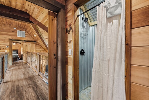 A wooden interior with a wooden floor, a metal door with a towel hanging on it, and a small window.