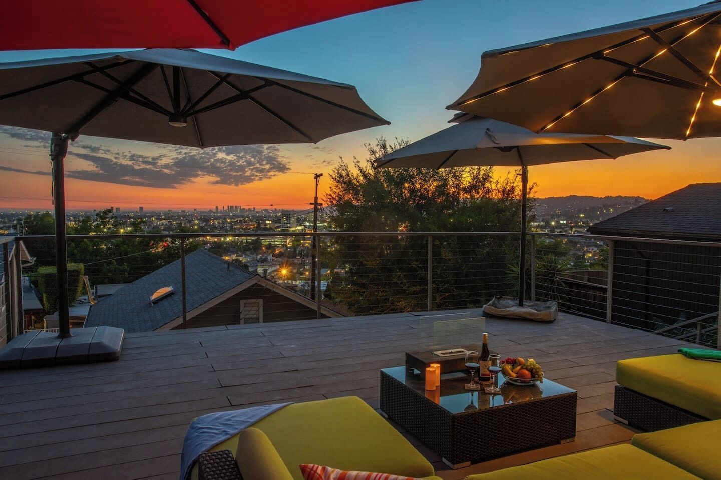 A rooftop terrace with outdoor seating, umbrellas, and a sunset view.