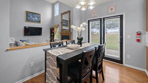 A dining area with a table set for four, a chandelier, a large mirror, and a fire extinguisher on the wall. - Pickerington Haven Home for 10 (Pickerington)