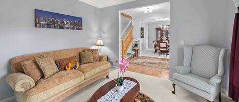 A living room with a sofa, armchair, coffee table, and a cityscape painting on the wall.