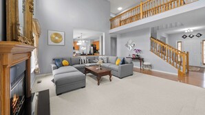A spacious living room with a fireplace, grey sofas, and a wooden staircase. - Pickerington Haven Home for 10 (Pickerington)