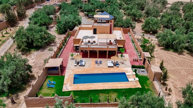 Vista aérea de un complejo turístico con piscina, mobiliario exterior y una zona de patio cubierta.