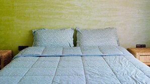 Una habitación con cama, aire acondicionado de pared, lámpara de madera y un tapete tejido.