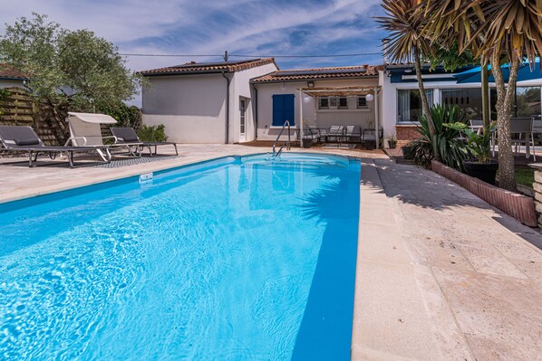 A swimming pool with lounge chairs and a patio area.