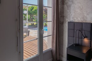 A room with a view of a wooden deck and a swimming pool.