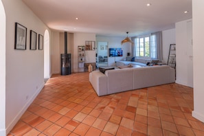 A spacious living area with a large sofa, a fireplace, and a television mounted on the wall. - Villa Zenorya (Fargues-Saint-Hilaire)