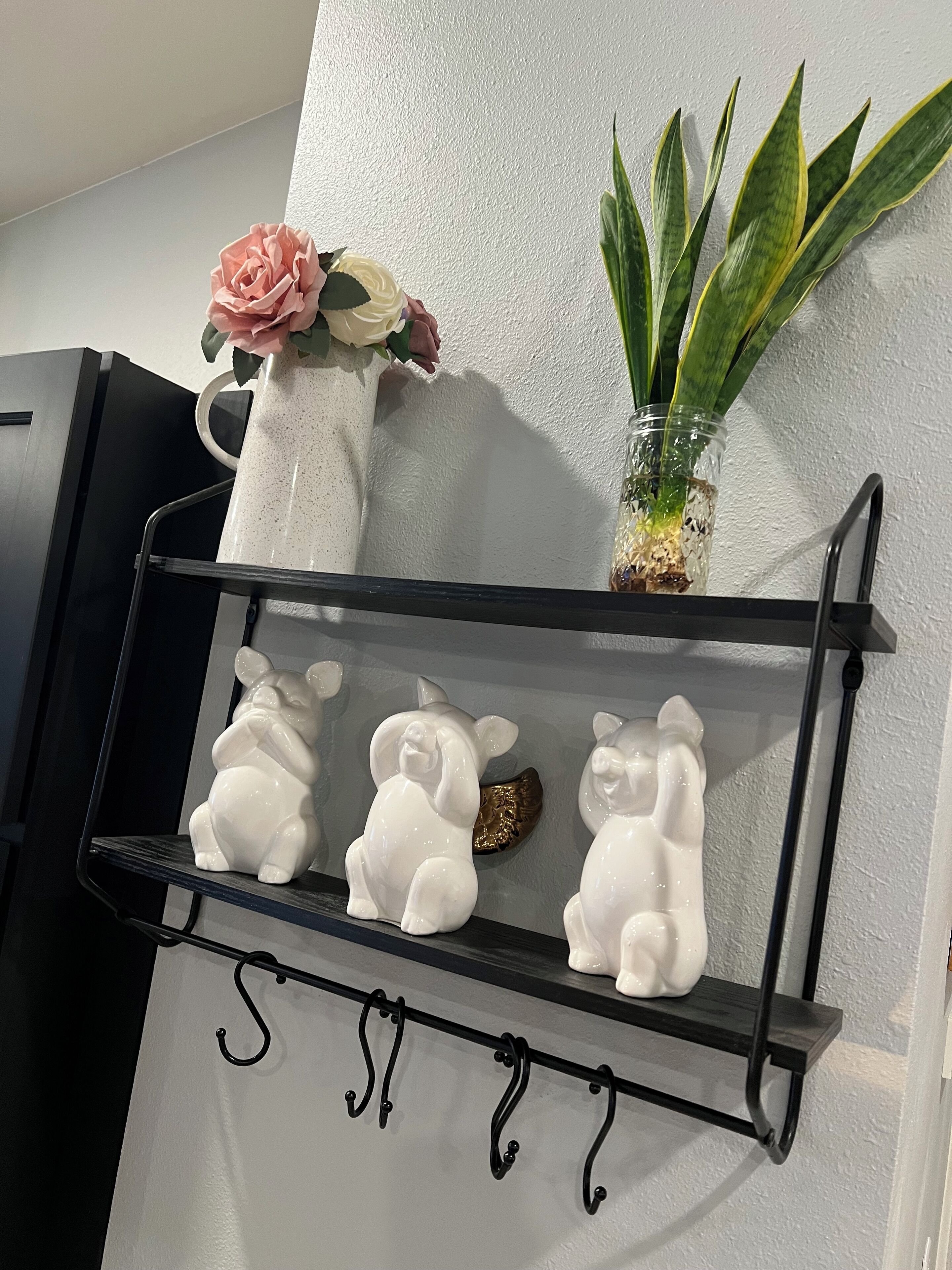 En hyld med pynteting, heriblandt en vase med blomster, en potteplante og tre keramikkaninfigurer.