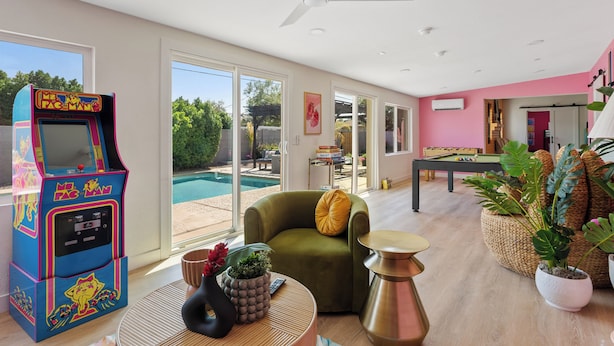 A spacious living area with a pool view, a Pac-Man arcade machine, and a cozy seating area. - Disco Dino: Pool, HotTub & Game Room Sleeps 18 (Scottsdale)