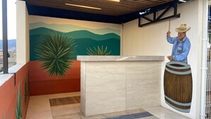 A reception area with a mural, a wooden ceiling, and a counter. - Casa Puro Verbo Candiani (Oaxaca)