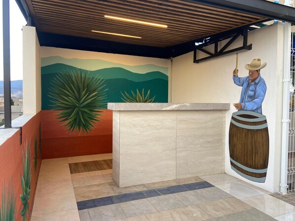 A reception area with a mural, a wooden ceiling, and a counter. - Casa Puro Verbo Candiani (Oaxaca)