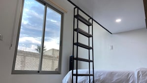 A bedroom with a large window, a bed, and a black metal ladder. - Casa Puro Verbo Candiani (Oaxaca)