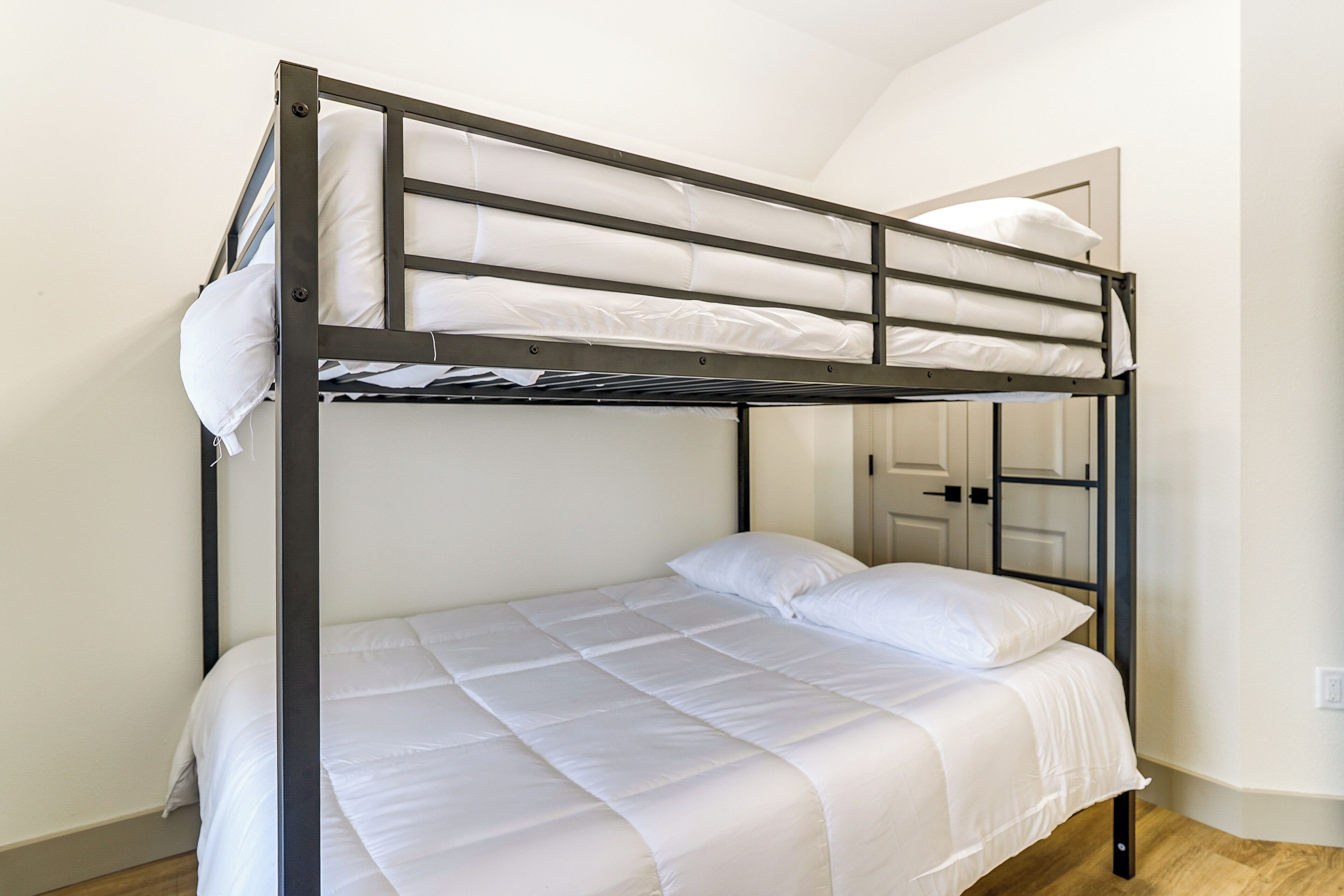 A bunk bed with white bedding and a metal frame.