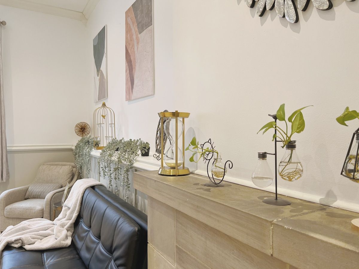 A living room with a leather sofa, a coffee table, and decorative items including a birdcage, a glass terrarium, and potted plants.