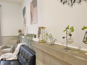 A living room with a leather sofa, a coffee table, and decorative items including a birdcage, a glass terrarium, and potted plants.