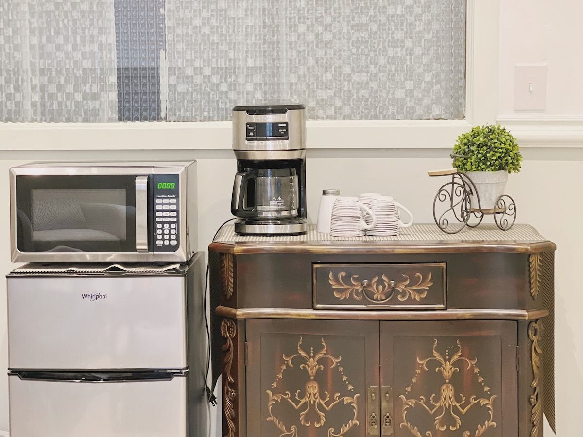 A kitchenette with a microwave, coffee maker, and a refrigerator.