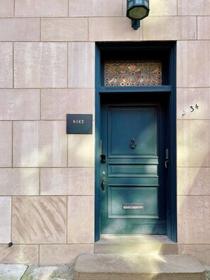 A dark green door with a brass knocker, a small window above it, and a house number sign. - Ramblei near Rittenhouse Sq | 1 bedroom – Unit A (Philadelphia)
