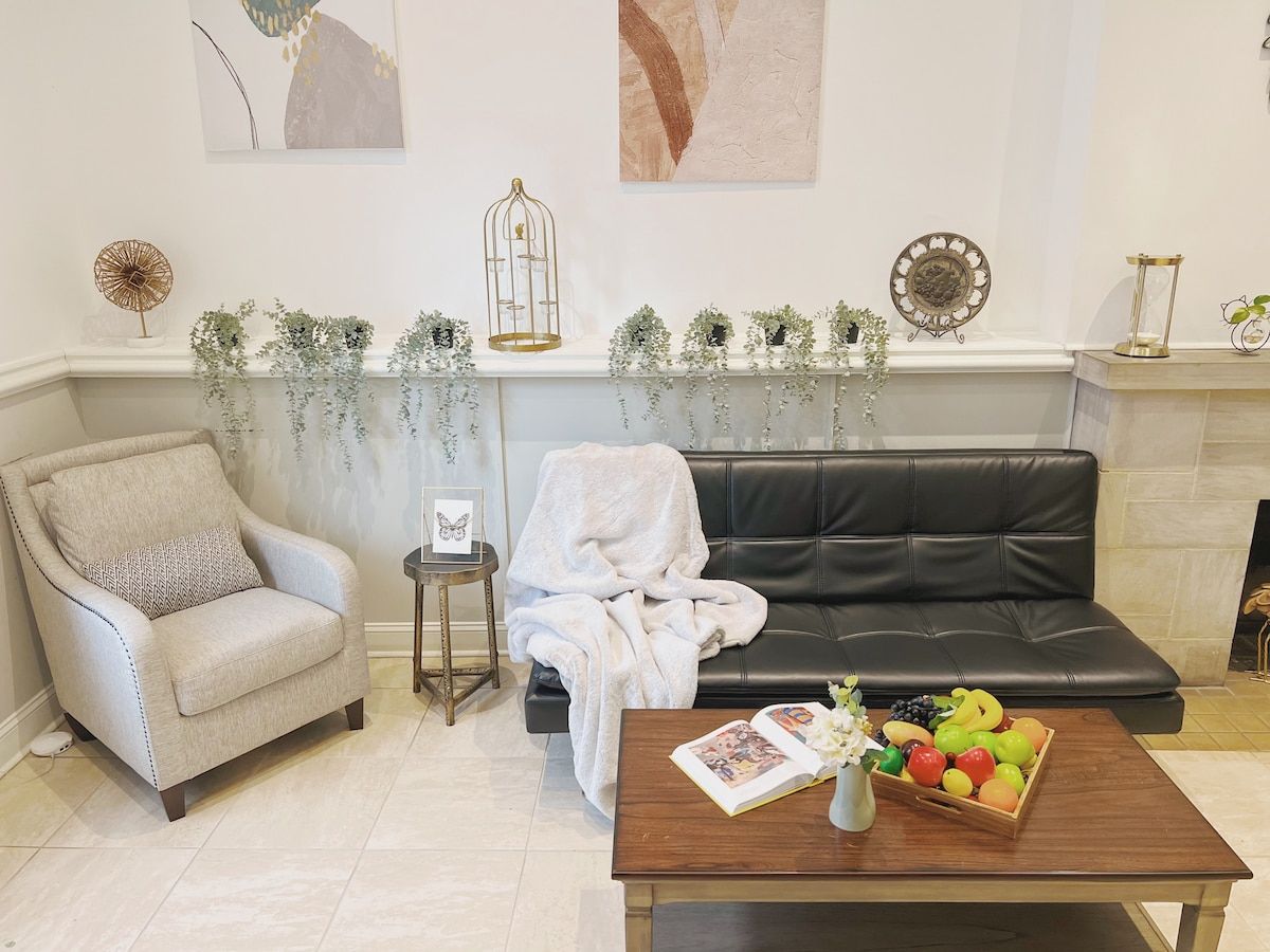 A living room with a sofa, armchair, coffee table with fruit, and decorative items.