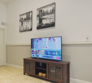A television on a wooden stand with a wall-mounted shelf below it. - Ramblei near Rittenhouse Sq | 1 bedroom – Unit A (Philadelphia)