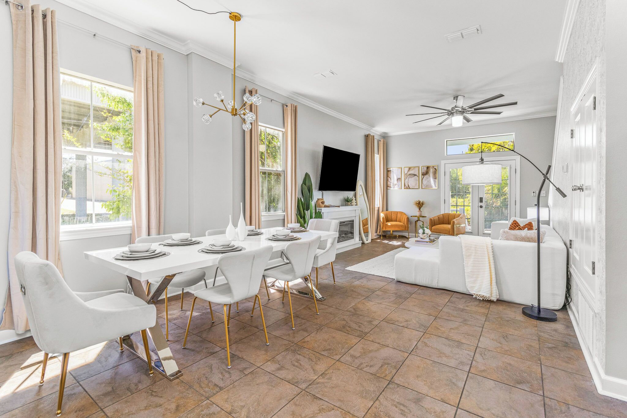 A spacious living room with a white sofa, a dining table with chairs, and a fireplace.