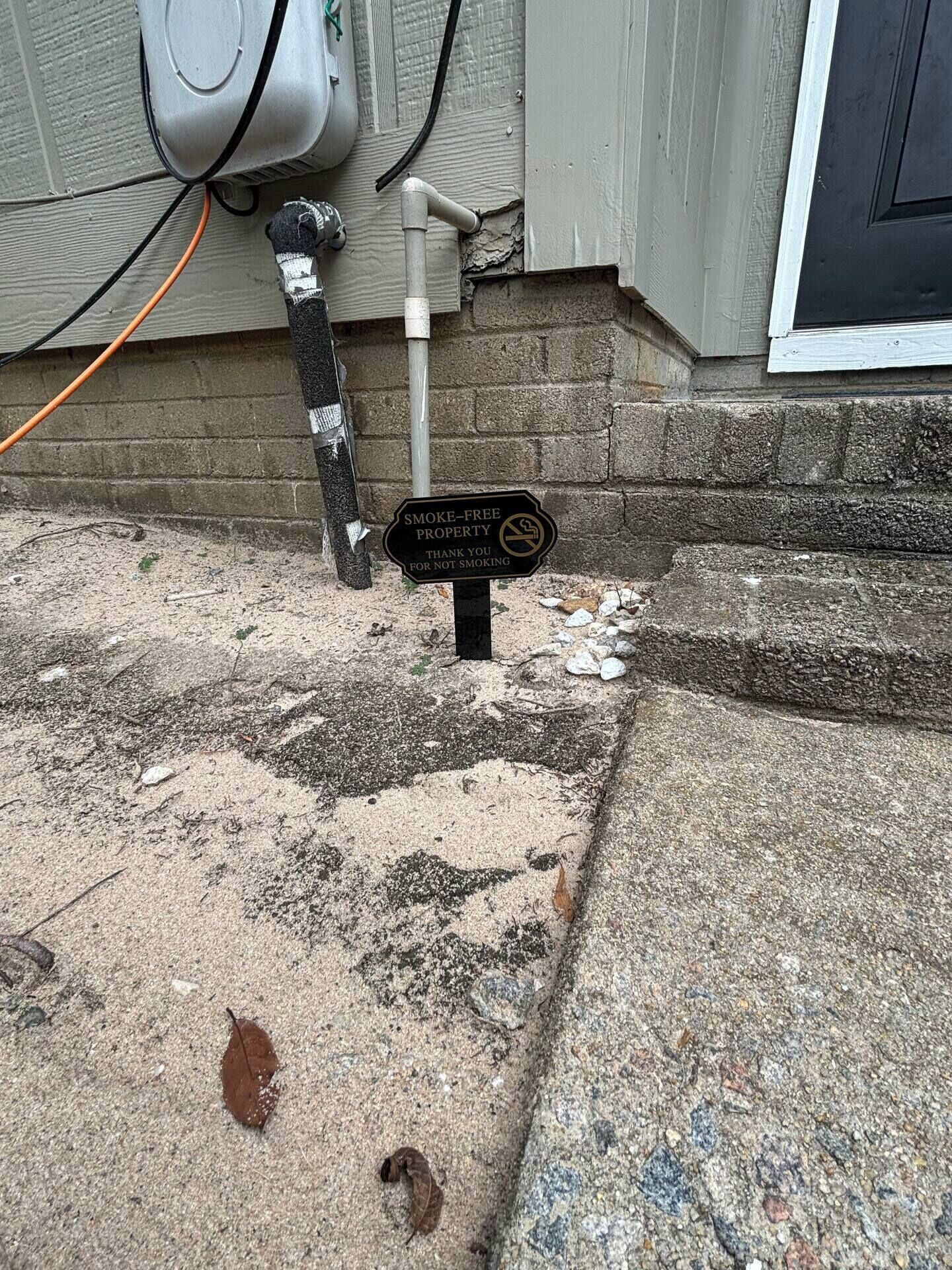 A concrete surface with a sign indicating a smoke-free property.