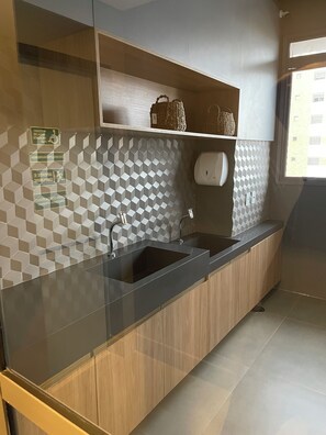 Una cocina moderna con encimera negra, armarios de madera, un salpicadero geométrico y un ventanal que aporta luz natural.