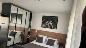 A modern hotel room with a bed, a sofa, a wardrobe, and a painting on the wall. - BEAUTIFUL AND COZY STUDIO (São Paulo)