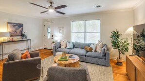 A modern living room with a grey sofa, a wooden coffee table, and a ceiling fan. - < 1 Mi to Ole Miss & The Grove! Charming Getaway (Oxford)