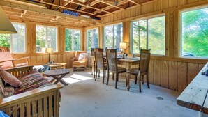 A wooden cabin interior with a dining table, chairs, and a sofa. - Waterfront Escape w/ Beach Access in Bridgton (Bridgton)