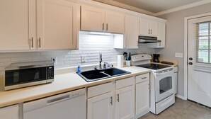 A modern kitchen with white cabinetry, a stainless steel microwave, a double sink, and a built-in oven. - Hike & Explore: Cheraw Apt 7 Mi to Lake Juniper! (Cheraw)