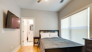 A bedroom with a bed, a nightstand, a TV mounted on the wall, and a window with blinds. - 9 Mi to Dtwn ATL: Pet-Friendly Apt w/ Yard (Atlanta)