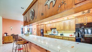 Una cocina con armarios de madera, encimera blanca y refrigerador de acero inoxidable.