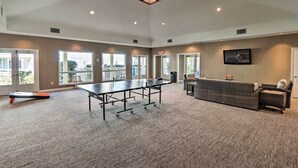 A spacious room with a ping pong table, a sofa, and a television. - Access to Folly Field Beach & Pools: Coastal Condo (Hilton Head Island)