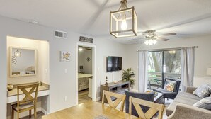 A well-lit living room with a dining area, a ceiling fan, and a television mounted on the wall. - Access to Folly Field Beach & Pools: Coastal Condo (Hilton Head Island)