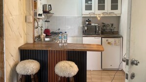 Eine kleine Küche mit Holzarbeitsplatte, zwei Barhocker, einem Kühlschrank, einer Mikrowelle und einem Toaster.