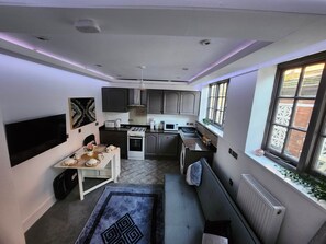 Een compacte keuken met moderne apparatuur, een eethoek met een televisie, en een gezellige zithoek met uitzicht op de omgeving.