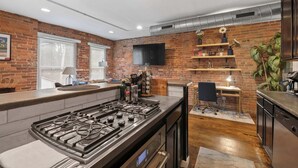 Eine moderne Küche mit Backsteinwand, Flachbildfernseher und Barbereich.