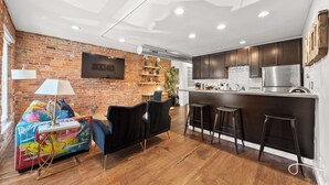 Eine moderne Küche mit dunklen Holzschränken, einem Edelstahlkühlschrank und einer Bar mit Barhocker.