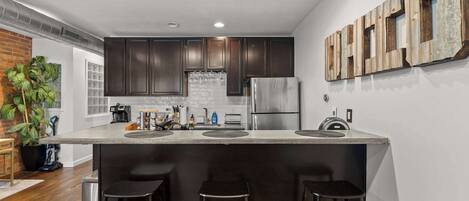 A modern kitchen with dark wood cabinets, stainless steel appliances, and a central island with stools.