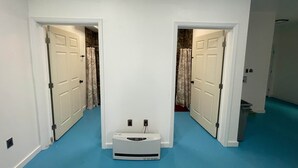 A hallway with two doors leading to bathrooms, a white wall, and a blue carpet. - Happy Trails Hideout #2 (Houston)