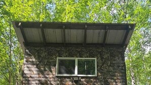 A small, single-room cabin with a metal roof, a window, and a door. - Camo Getaway Cabin #7 (Houston)