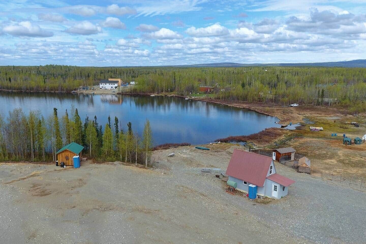 A lakeside property with a small cabin, a larger building, and a dock.