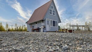 A two-story house with a sloped roof, a front porch, and a gravel driveway. - Bass Farm: Lake View Loft Cabin (Houston)