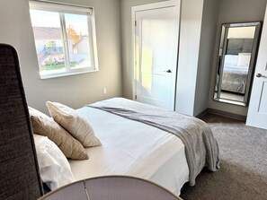 Une chambre à coucher avec un lit, une fenêtre, une porte et un miroir.