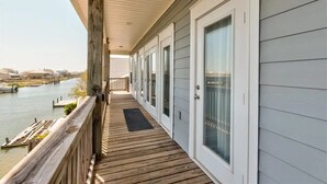 Ein überdachter Balkon mit Holzboden, der auf ein Gewässer und einen Steg blickt.