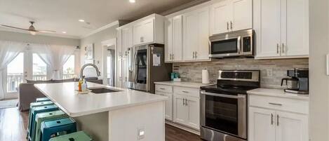 A modern kitchen with white cabinets, stainless steel appliances, and a central island with stools.