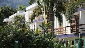 Un hôtel moderne à plusieurs étages, entouré d’une végétation luxuriante et de palmiers.