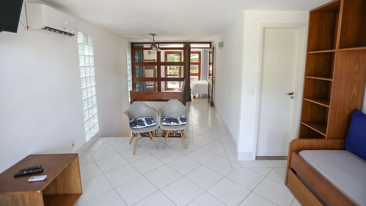 A living room with a sofa, a wooden shelf, and a dining area with two chairs.
