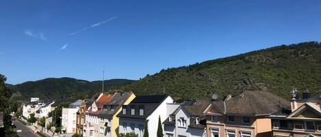 A row of colorful townhouses along a street with a clear sky and a hill in the background.