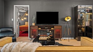 Una sala de estar moderna con un televisor de pantalla plana grande, una chimenea, un trípode y una estantería.