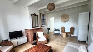 A living room with a TV, fireplace, wicker furniture, and a dining area with chairs and a table.